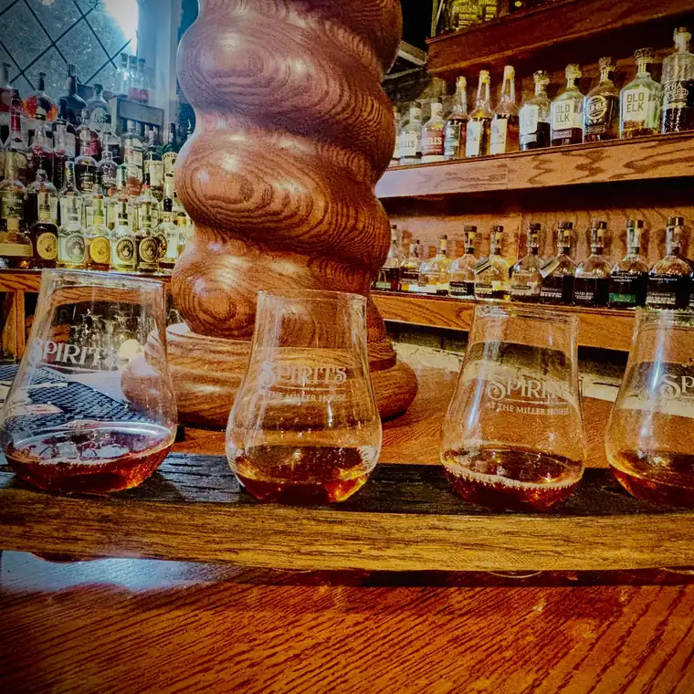 A flight of bourbon on the bar beside the carved spiral column