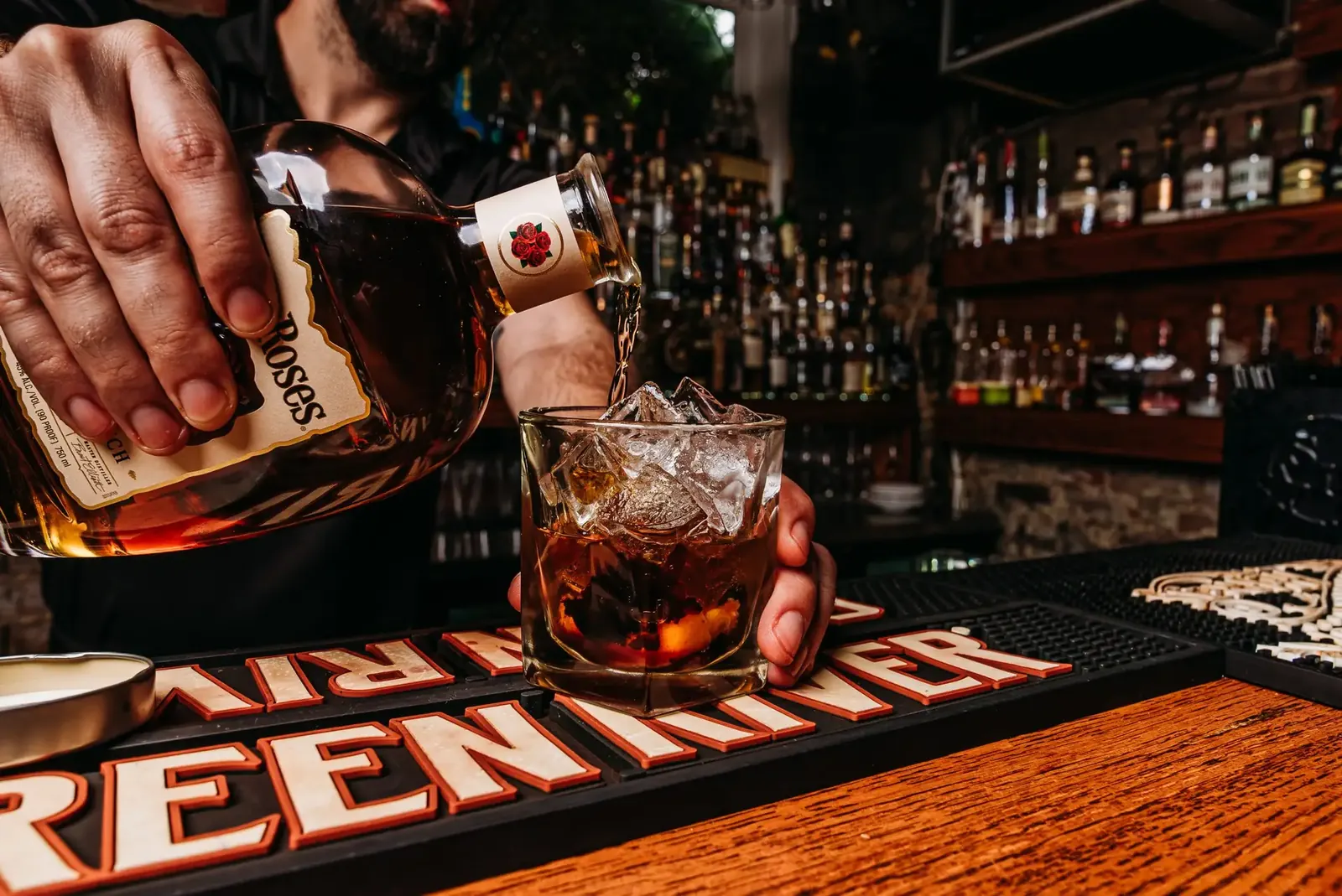A bartender pouring bourbon over ice