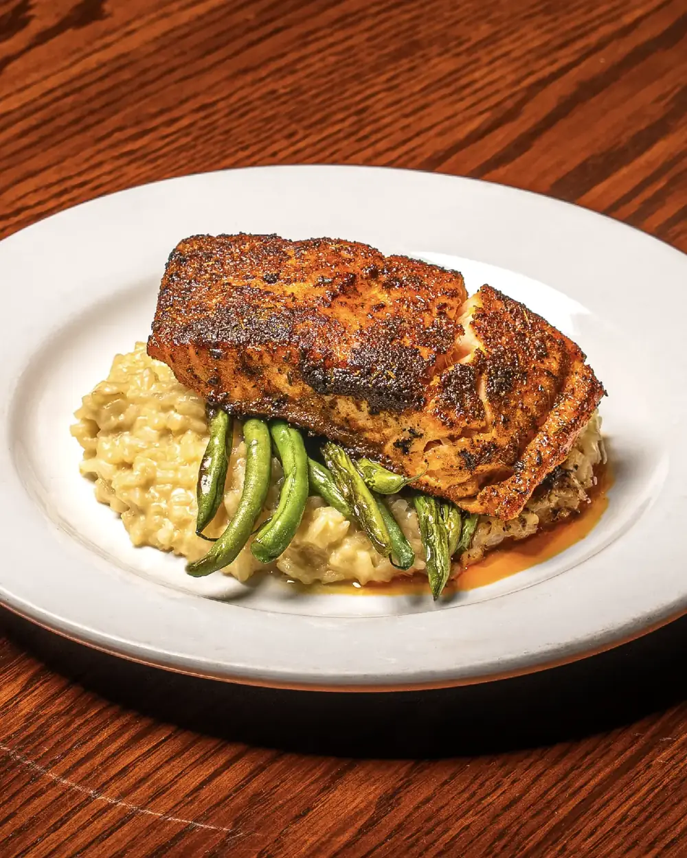 A plated fillet over risotto with green beans